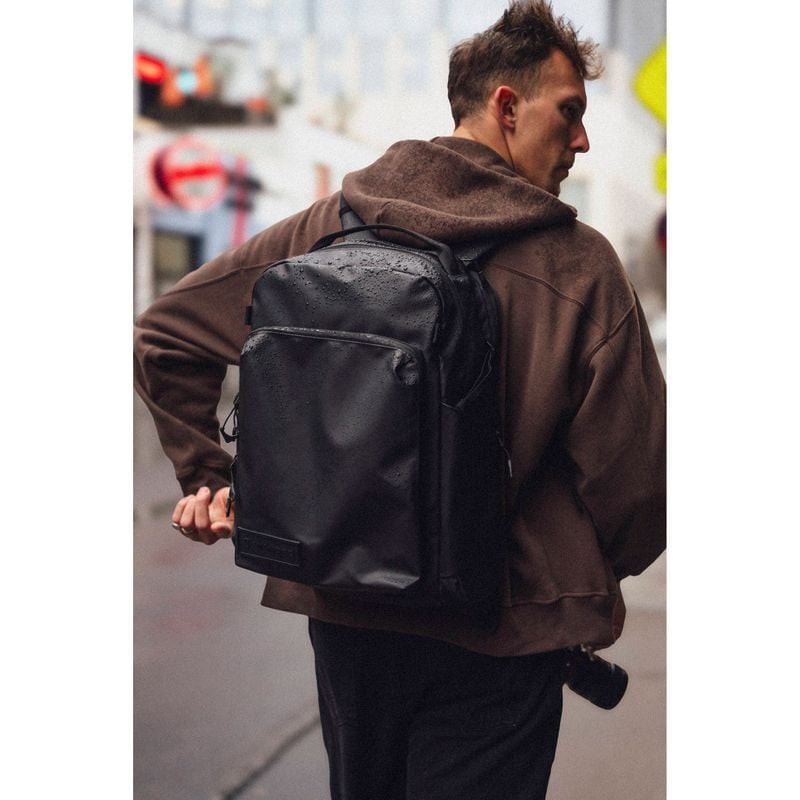 Homme portant le sac à dos WANDRD PRVKE Pocket 31L en rue urbaine sous la pluie, démontrant sa résis