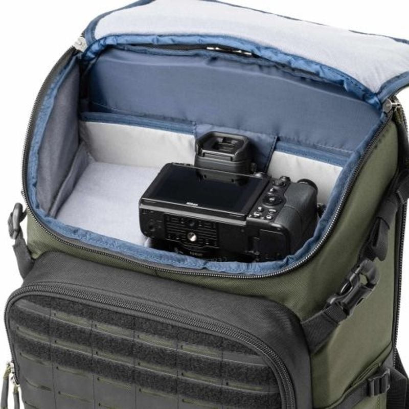 Sac à dos Think Tank DarkLight 25L Montane Green posé sur un rocher dans un décor extérieur pittores