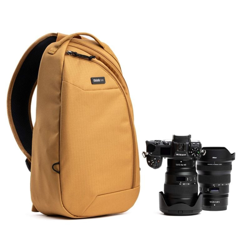 Sac sling Think Tank TurnStyle 11L Golden Hour à côté d’un appareil photo hybride Nikon et d’objecti