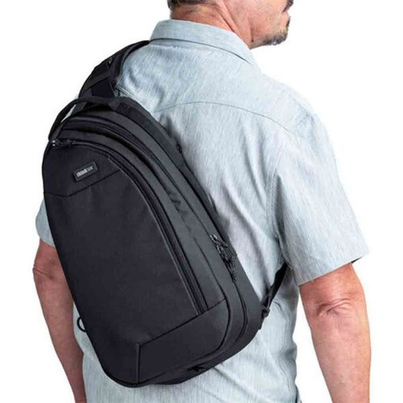 Photographe en milieu urbain portant le THINK TANK TURNSTYLE 11L ASPHALT BLACK en bandoulière, accéd