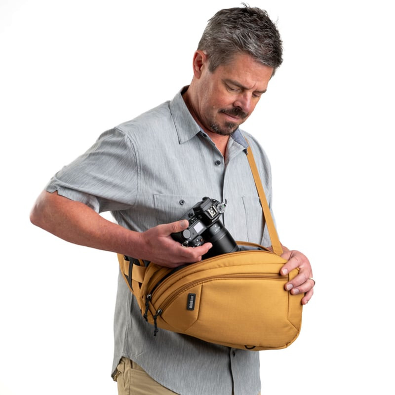 Photographe en ville portant le sac photo rotatif THINK TANK TURNSTYLE 8L GOLDEN HOUR, accès rapide 