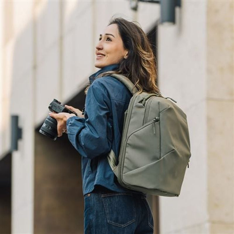 Photographe portant le sac à dos PGYTECH OneGo Lite 16L Vert Forest tenant un appareil photo hybride