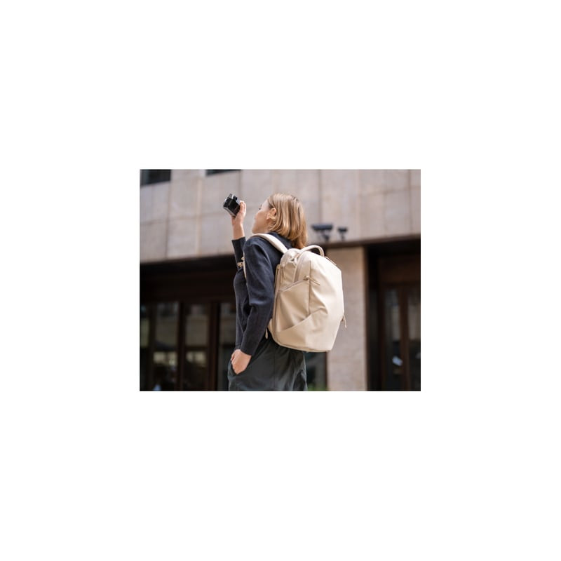 Le PGYTECH ONEGO LITE BACKPACK 12L CREME porté par un photographe en ville, discret et fonctionnel.
