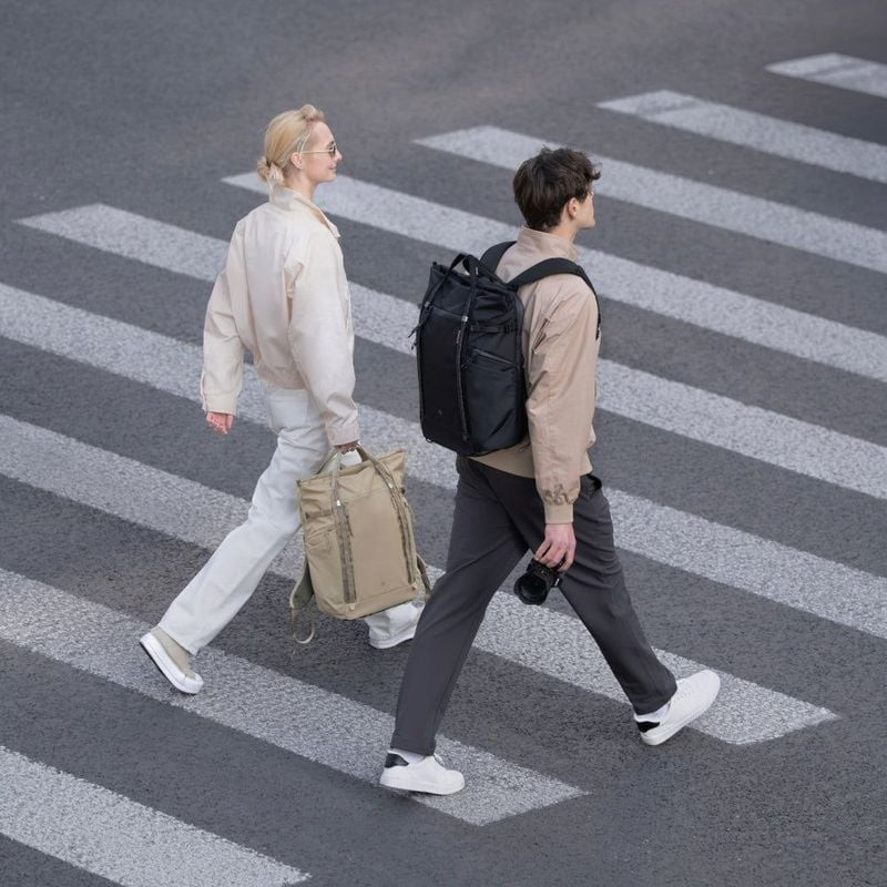 Vue du dessus : couple traversant la rue, la femme porte le PGYTECH OneGo Roamer Tote 18L Sable, l'h