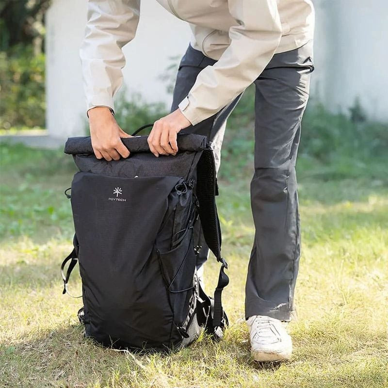 Personne ajustant la fermeture roll-top d'un sac à dos PGYTECH OnePro Ultralight 30L noir en extérie