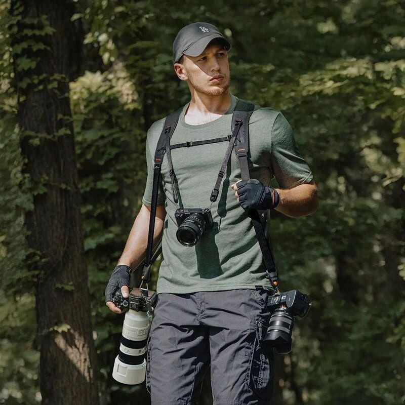 Photographe en forêt portant trois appareils photo sans les mains avec le harnais double épaule PGYT