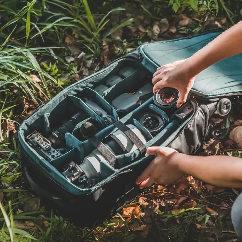 Sac à dos photo PGYTECH ouvert sur l'herbe, avec séparateurs DIY contenant objectifs, boîtiers et ac