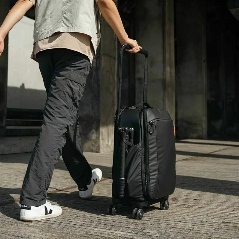 Photographe roulant le sac à dos photo PGYTECH par sa poignée télescopique sur un trottoir urbain