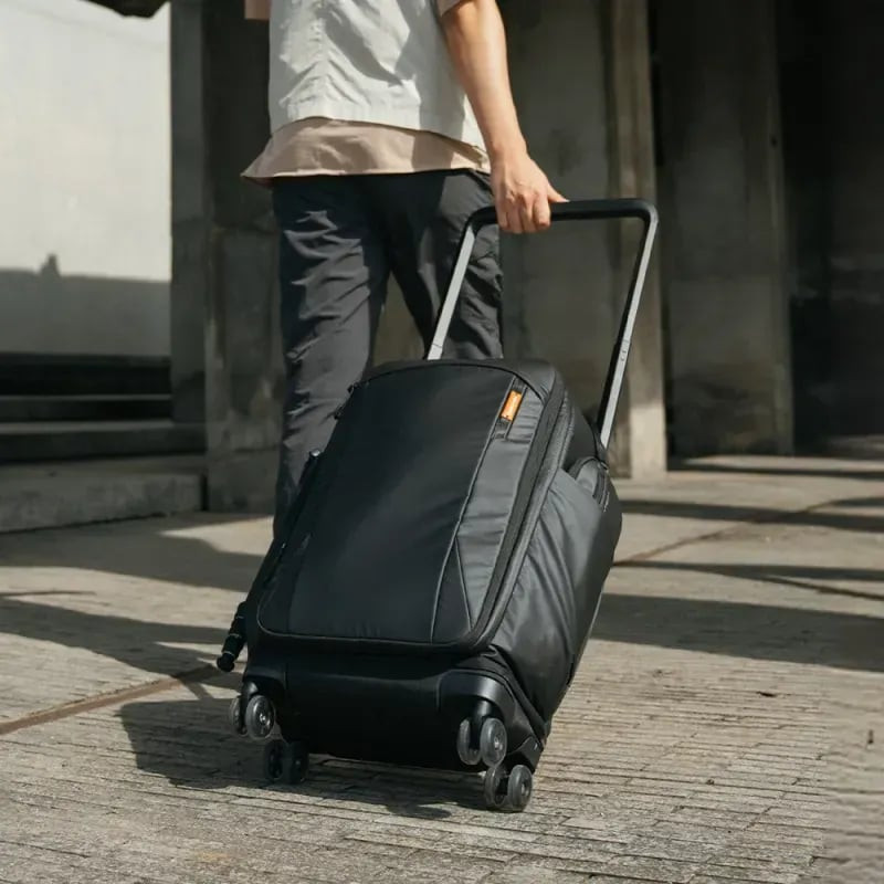 Sac à dos roller PGYTECH 30L tiré par sa poignée télescopique dans une rue urbaine ensoleillée