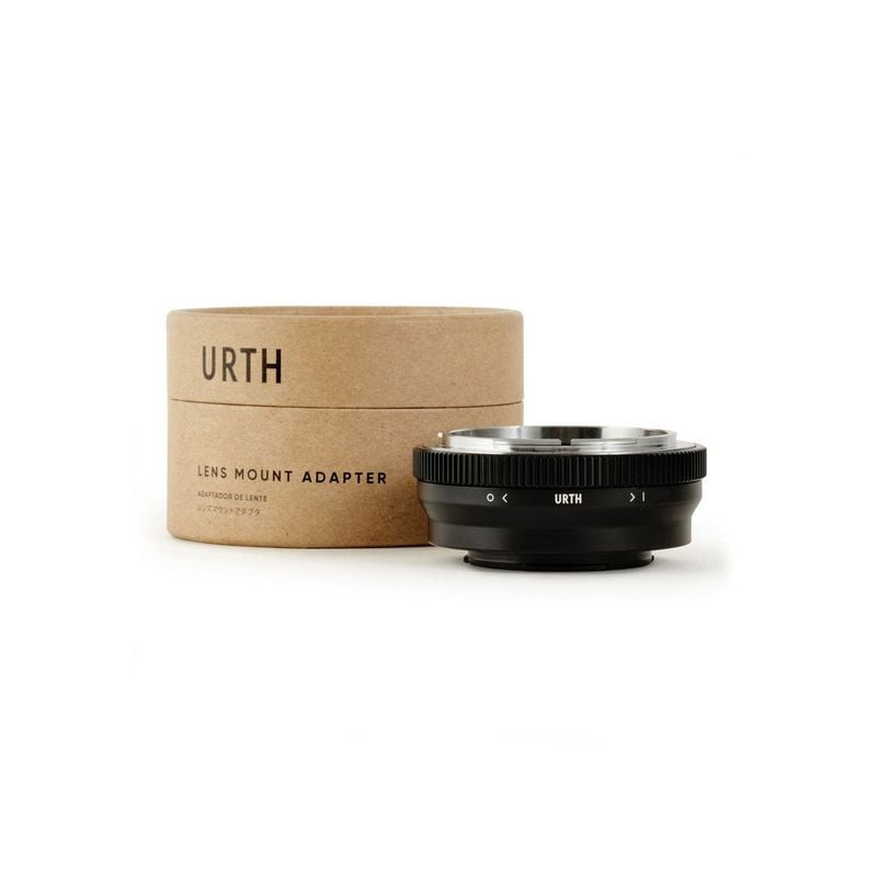 Adaptateur de monture Urth exposé à côté de sa boîte cylindrique en papier kraft imprimée du logo Ur