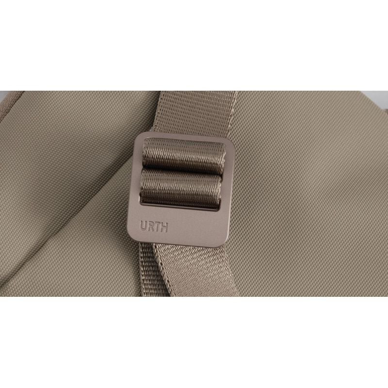 Détail de la boucle curseur métallique Urth et de la sangle tissée sur le tissu vert olive de la poc