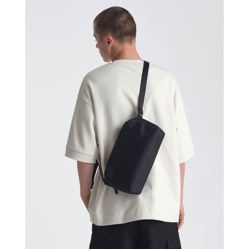 Modèle portant le sac photo Urth Dolomite 5,1 L en bandoulière dans le dos sur un t-shirt crème