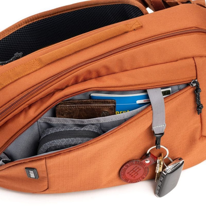 Poche avant ouverte du sac sling TurnStyle 8L Urban Rust contenant un portefeuille, des cartes et de
